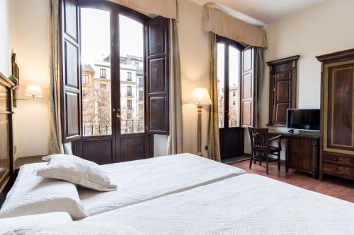 格拉纳达Hotel Plaza Nueva的卧室配有一张床、一张书桌和窗户。