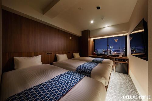 东京HOTEL AMANEK Asakusa Ekimae的酒店客房设有两张床和大窗户。