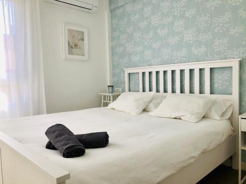 加的斯Apartamento Ecuador的卧室配有白色大床和蓝色壁纸