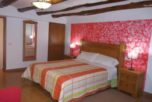 Las Cuevas de CañartCasa Rural La Buhardilla的一间卧室设有一张床和红色的墙壁
