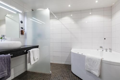 乌普萨拉克拉丽奥吉莱特酒店的白色的浴室设有浴缸和水槽。