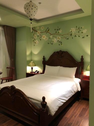 河内Le Grand Hanoi Hotel - The Oriental的卧室配有一张铺有白色床单的床,墙上挂着鲜花。