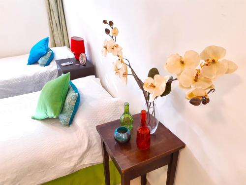 门多萨Departamento Encantador monoambiente Domaine Laborde I的客房设有两张床和一张带花瓶的桌子。