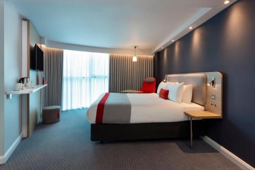 伦敦快捷假日皇家公园酒店的酒店客房,配有一张床和一张红色椅子