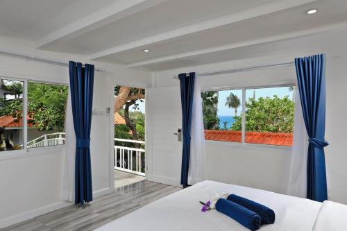 卡塔海滩Kata White Villas的一间卧室配有蓝色窗帘和一张享有海景的床。