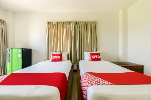 是拉差OYO 350 Mae Saeng Place的配有红色和白色床单的客房内的两张床