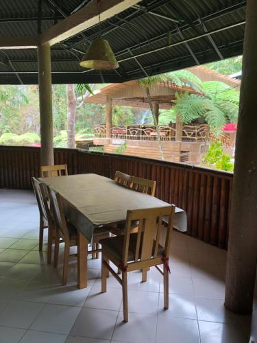 杜马格特Pulangbato Falls Mountain Resort的天井配有桌椅、桌子和门廊