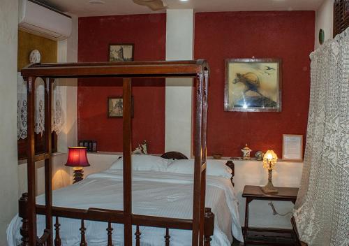 孟买The Ferreiras的一间卧室设有天蓬床和红色墙壁