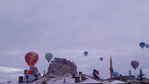 乌奇希萨尔Capiedra Hotel的一组热气球飞越一座建筑物