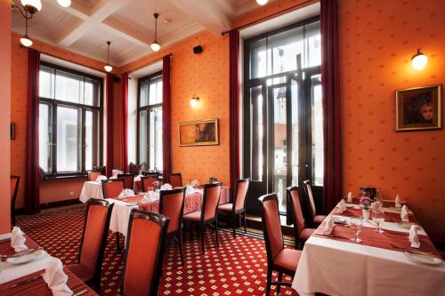 塔林Hestia Hotel Barons Old Town的一间设有桌椅的餐厅,位于带橙色墙壁的房间