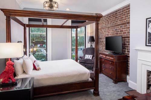 萨凡纳环河街酒店的一间卧室设有一张天蓬床和一台电视机。