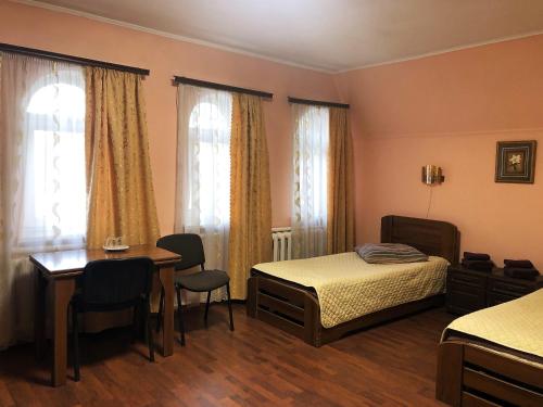 ChervonogradComfort Hotel的一间卧室配有两张床和一张桌子及椅子