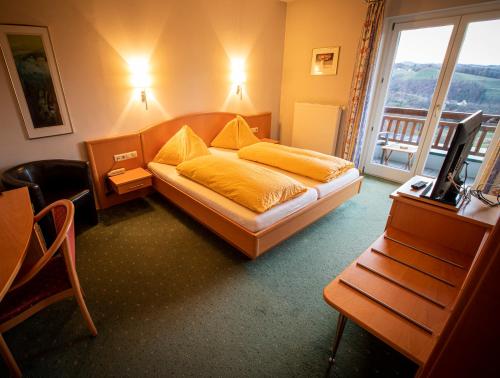 加姆利茨eckbergerhof的一间卧室配有一张床、一台电视和一个阳台