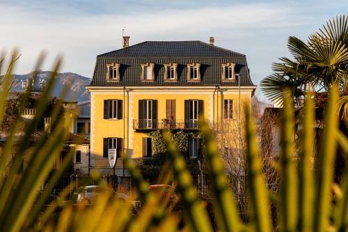 韦尔巴尼亚Hotel Casa Camilla的黄色的房子,有黑色的屋顶和棕榈树