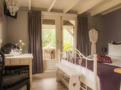 NumansdorpBed & Breakfast De Schuur Inn的一间卧室配有一张床、一张书桌和一个窗户。