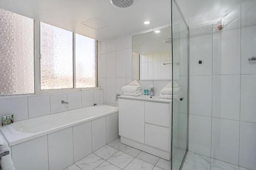 黄金海岸多徹斯特海滩上酒店的白色的浴室设有浴缸和玻璃淋浴间。