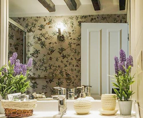 托莱多Tres Lunas的浴室设有水槽、镜子和紫色的鲜花