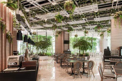 吉隆坡Komune Living的餐厅设有桌椅和植物天花板。