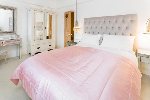 艾纯查姆Stamford Park Road by YourStays!的白色卧室配有粉红色的床和水槽