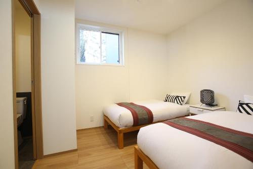 白马村Apartments Hakuba的一间卧室设有两张床和窗户。