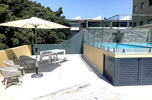 悉尼曼利中心公寓的一个带桌子和遮阳伞的庭院和一个游泳池