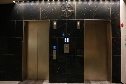大阪PORTA INN bentencho的两部电梯,位于一栋有黑色瓷砖的建筑中