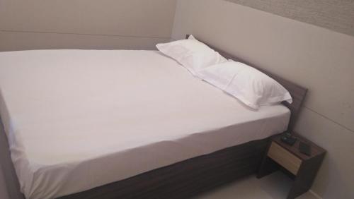 德里久尔LEMON RESIDENCY By Chungath的一张带白色床单和枕头的床
