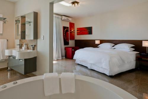 开普敦Camps Bay Ruby Suite的卧室配有白色的床和浴缸
