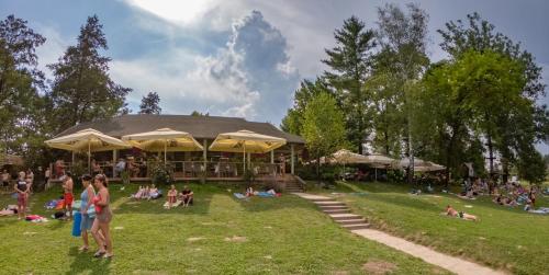 梅特利卡Holiday resort & camping Bela krajina - river Kolpa的一群人坐在一座建筑前面的草上