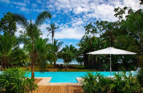 别霍港卡默莱昂精品酒店的一个带遮阳伞和棕榈树的度假游泳池