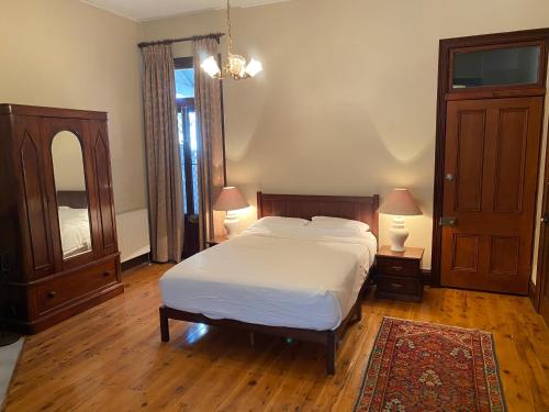 亚斯Yass Central Bed & Breakfast的一间卧室配有一张床、两盏灯和一面镜子