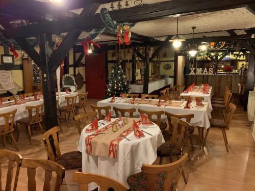 巴特朗根萨尔察Gasthaus Zur Weintraube的一间设有白色桌椅和圣诞树的餐厅