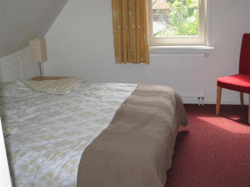 登堡Koperwiek Texel的卧室内的一张床位,配有红色椅子和窗户