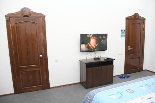 塔什干Nurziyo Guest House的一间卧室配有一张床,墙上配有电视