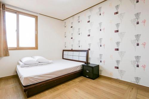 济州市济州特别旅馆的卧室配有带白色墙壁和窗户的床