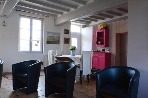 Berville皮勒特农庄旅馆的厨房配有黑色椅子、桌子和粉红色橱柜。