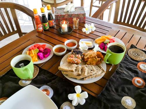 佩母德兰巴厘岛欧亚瑟度假酒店的一张木桌,上面摆放着早餐食品和饮料