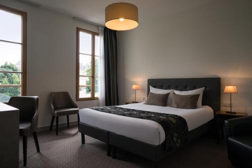尼奥尔Hôtel du Moulin的酒店客房设有一张床和两个窗户。