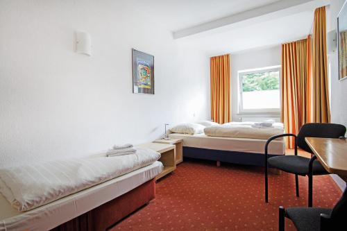 吕贝克Baltic Hotel Lübeck的客房设有两张床、一张桌子和一张书桌。