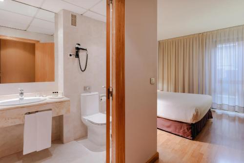 萨拉戈萨Hesperia Zaragoza Centro的浴室设有床、卫生间和水槽。