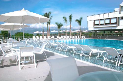 布卡拉曼加布卡拉曼加度假酒店的一座带白色椅子和遮阳伞的游泳池,位于一座建筑旁边