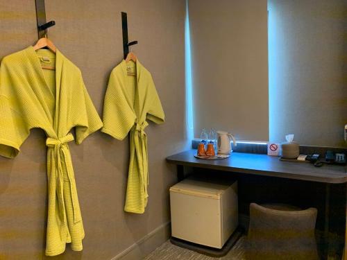 曼谷Tango Vibrant Living Hotel - SHA Extra Plus的酒店客房的墙壁上挂着黄色的毛巾