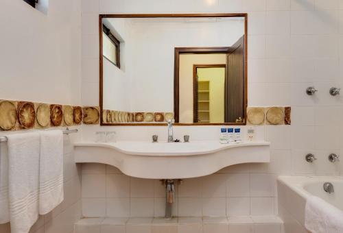 PanoramaMalaga Hotel的一间带水槽、浴缸和镜子的浴室