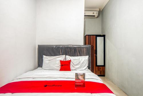 雅加达RedDoorz near Graha Cijantung Mall的房间里的床上红色枕头