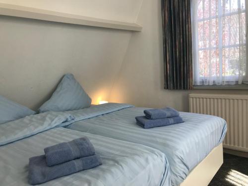 卑尔根De Specht的一间卧室配有两张床和蓝色毛巾。