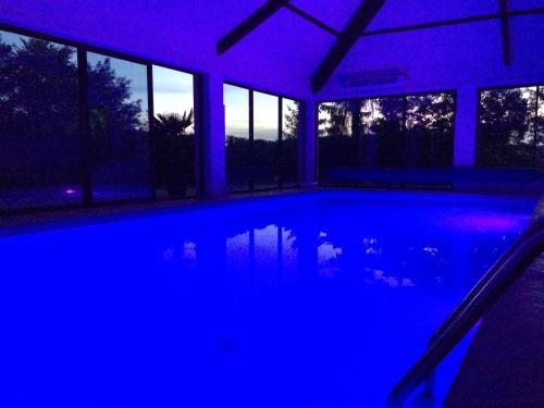Saint-Léger-sur-DheuneLes Lodges的紫色灯的房子里的一个空游泳池