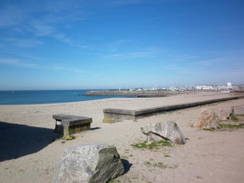 盖朗德Kerstunt Chambre d'hôtes Relais Motards的海滩上的长凳,上面有岩石和海洋