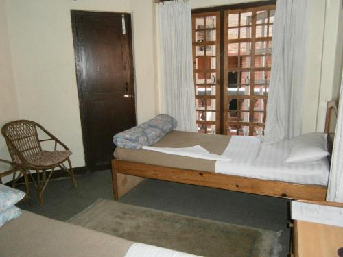 加德满都红色星球酒店的一间卧室设有一张床、一个窗口和一把椅子