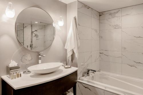 蒙特利尔Saint-Sulpice Montréal的一间带水槽、浴缸和镜子的浴室