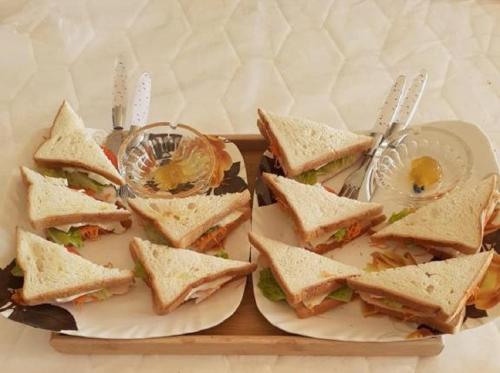 亭可马里WoodyCrest的托盘上的两盘三明治,托盘上放有餐具